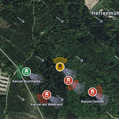 Satellitenkarte des Beispielreviers mit Wald, Wiesen, Windpfeilen und den Sitzen in Ampelfarben, oben rechts der Ortsname Herrenmühle.